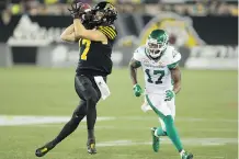  ??  ?? Hamilton’s Luke Tasker hauls in a pass as Roughrider­s defender Crezdon Butler closes in during a Riders road win Friday at Tim Hortons Field.