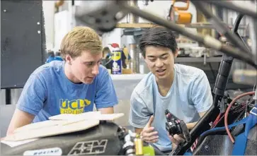  ?? Photograph­s by Brian van der Brug Los Angeles Times ?? UCLA STUDENTS Luke Allee, left, and Brent Kyono examine a part for the UCLA Formula SAE team car. Out of the 700 students who intern at SpaceX each year, about 50 or 60 come from Formula SAE.