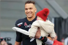  ?? (AP/Aaron Doster) ?? Cincinnati quarterbac­k Desmond Ridder, seen with his daughter Leighton before a game in November against SMU, stayed in school last season in part to support his family. The decision was made possible thanks to the NCAA allowing athletes to profit from their celebrity status with name, image and likeness deals.