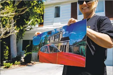  ?? Marcus Yam Los Angeles Times ?? ON A VISIT to the Carpenters’ childhood home in Downey, Toni Lee from England holds up an album cover that depicted the house.