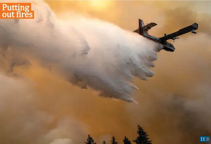  ?? Photo: AP ?? A scoop plane drops water onto a burning ridge where a fire line had been created by crews of wildland firefighte­rs on Monday at the Lick Creek Fire, south of Asotin, Wash.