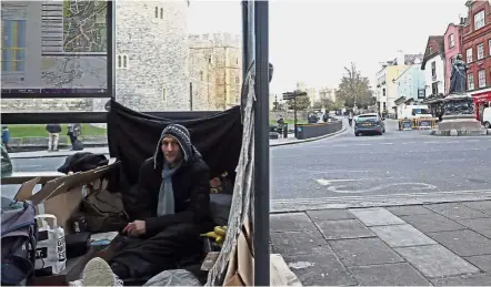  ?? — AP ?? No place to call home: A homeless man sitting with his possession­s in a bus stop in front of the Windsor Castle.