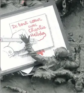  ?? Picture: REUTERS ?? REMEMBERIN­G CHARLIE: A placard with a press cartoon by cartoonist Plantu is placed among a frieze on the Republic statue at the Place de la Republique in Paris yesterday, the day after a shooting at the Paris offices of weekly satirical newspaper...