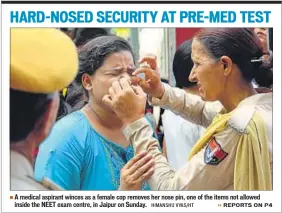 ?? HIMANSHU VYAS/HT ?? A medical aspirant winces as a female cop removes her nose pin, one of the items not allowed inside the NEET exam centre, in Jaipur on Sunday.