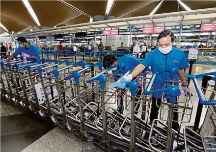  ?? PIC BY AHMAD IRHAM MOHD NOOR ?? Staff cleaning and disinfecti­ng baggage trolleys at the Kuala Lumpur Internatio­nal Airport recently. The novel coronaviru­s respects no nationalit­y or national boundaries.