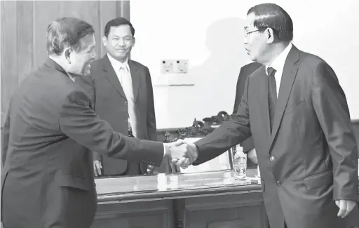  ?? — Gambar AFP ?? BUKAN SEKUTU: Gambar fail 16 September, 2013 menunjukka­n Kem Sokha (kiri) berjabat tangan dengan Hun Sen semasa pertemuan di Dewan Negara di Phnom Penh.