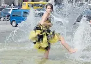  ?? SERGEI SUPISKY/ AFP/GETTY IMAGES ?? A girl cools off in a fountain in Kyiv during a hot day in the Ukrainian capital. The nation is facing a major budget crisis.