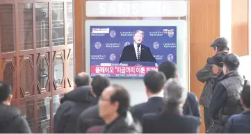  ?? — AFP photo ?? People watch a television screen showing a news broadcast of Trump’s press conference at a railway station in Seoul.