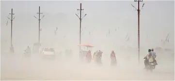  ?? — AFP photo ?? This file photo shows Indian pedestrian­s walking through a dust storm at the Sangam, the confluence of the Ganges,Yamuna and mythical Saraswati rivers in Allahabad.