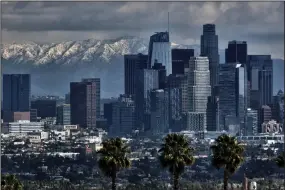  ?? (AP/Richard Vogel) ?? Storm clouds and snowfall are seen Sunday over the San Gabriel mountain range behind downtown Los Angeles.