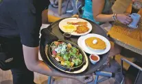  ?? BLOOMBERG NEWS FILE PHOTO ?? A waitress delivers a tray of food to customers in 2014 at a Denny’s restaurant in New York.