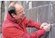  ??  ?? Salvator-Pfarrer Martin Winterberg zeigt die maroden Steine an der „Platte“, die später saniert werden sollen.