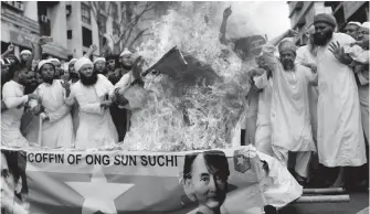  ?? AP ?? Islamic activists burn the national flag of Myanmar and a mock coffin of Myanmar leader Aung San Suu Kyi during a rally Friday in Dhaka, Bangladesh, to denounce the persecutio­n of Rohingya Muslims.