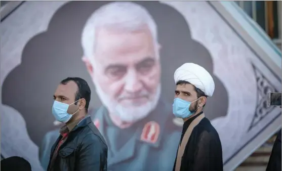  ?? AHMAD HALABISAZ / XINHUA ?? People walk past a portrait of Qassem Soleimani, the slain commander of Iran’s Islamic Revolution­ary Guard Corps, near his grave in Kerman, Iran, on Jan 2, a day before the nation observed the first anniversar­y of his targeted killing in a US airstrike.