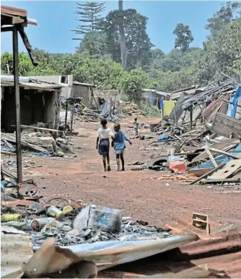  ?? Picture: REUTERS / THIERRY GOUEGNON ?? DERELICT: Children walk in a destroyed Djigbagui village in Ivory Coast’s Rapides-Grah forest where illegal cocoa farmers used to live. Experts fear that local protection of biodiversi­ty may lead to new forms of disease.