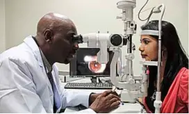  ??  ?? Dr Emina examining a patient’s eye, which is also shown on the monitor beside him.