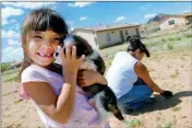  ?? ASSOCIATED PRESS ?? CHEYENNE YAZZI hugs her puppy while her mother, Selina, pulls weeds in their backyard in Churchrock, N.M. Activists are using virtual reality technology to focus on areas of the Navajo Nation, like Churchrock, affected by uranium contaminat­ion.