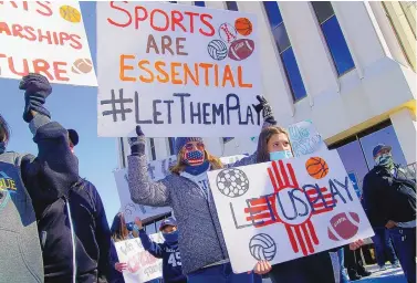  ?? ADOLPHE PIERRE-LOUIS/JOURNAL ?? Laura Lyle, left, and her 14 year-old daughter, Ally Lyle, hold signs during a protest at Albuquerqu­e Public Schools headquarte­rs Sunday. Ally Lyle, a La Cueva freshman who plays soccer and basketball, said she thinks it’s unfair that students in other states get to play sports.