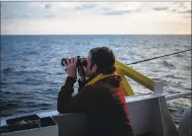  ?? Federico Scoppa AFP/Getty Images ?? A MEMBER of the German rescue group Sea-Watch keeps an eye out. The group says it rescued 47 people from a vessel off Libya the day after another boat sank.