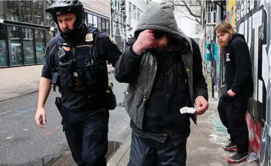  ?? ?? ► Un oficial de policía conduce a un hombre que fue sorprendid­o fumando fentanilo, en Portland.