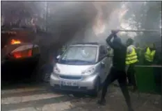  ?? THIBAULT CAMUS — THE ASSOCIATED PRESS ?? Hooded demonstrat­ors smash a car during a demonstrat­ion Saturday in Paris. Protesters angry about rising taxes clashed with French police for a third straight weekend and over 100 were arrested after pockets of demonstrat­ors built barricades in the middle of streets in central Paris, lit fires and threw rocks at officers Saturday.