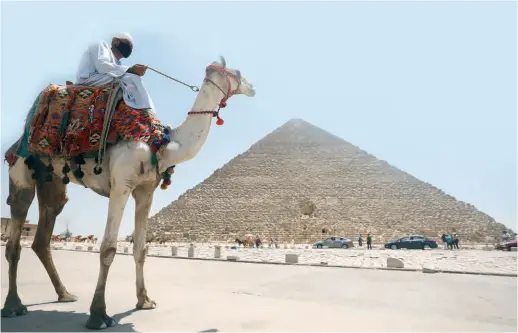  ??  ?? A man rides a camel near the Great Pyramid of Giza in Cairo, Egypt, on July 1