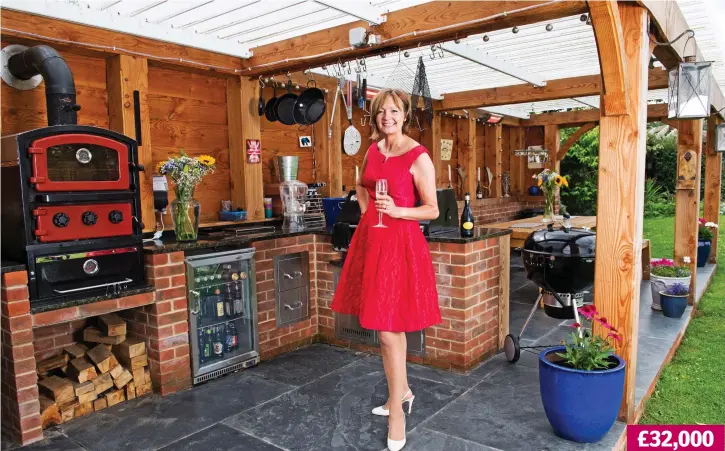  ??  ?? Alfresco dining: Jo Hughes in her large outdoor kitchen, which includes a pizza oven, two built-in barbecues, a grill, sink, drinks fridge and adjoining seating area