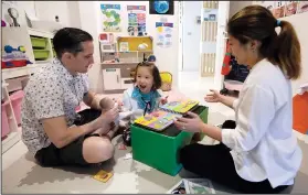  ?? (AP/Sakchai Lalit) ?? Richard Poulin (left) and Judy Wei (right) work with their daughter, Rylae-Ann, on Jan. 14 during a physical and cognitive therapy session at their home in Bangkok.