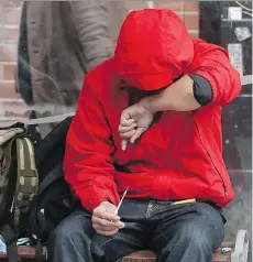  ?? JONATHAN HAYWARD/THE CANADIAN PRESS ?? A man holds a needle after injecting himself at a bus shelter in the Downtown Eastside. Vancouver Fire and Rescue Services reported 207 overdose response calls for the week ending Sunday.