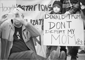  ?? — WP-Bloomberg photo ?? A young boy and his mother attend a rally at Lafayette Square in the District of Columbia to protest the recent raids country-wide by US Immigratio­n and Customs Enforcemen­t. Hispanic law makers wrote that “these raids have struck fear in the hearts of the immigrant community.”