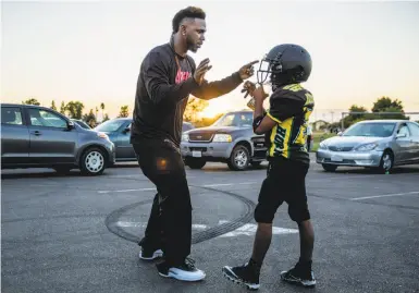  ?? Photos by Santiago Mejia / The Chronicle ?? Jamahl Mackey gives his son, Jamahl Jr., football tips during team practice for the Sacramento Jr. Hornets.