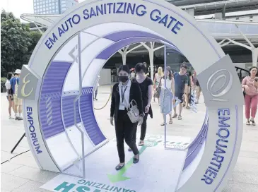  ?? JINAKUL APICHIT ?? Shoppers walk through a tunnel designed to automatica­lly spray sanitiser at the EmQuartier shopping mall in Bangkok.