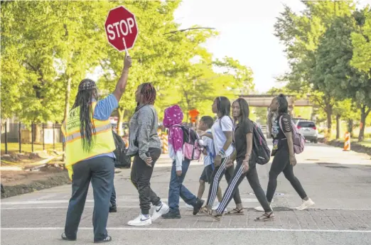  ?? ASHLEE REZIN/SUN-TIMES FILE ?? A crossing guard helps students and parents cross the street safely near Willa Cather Elementary School in East Garfield Park in August.