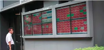  ?? — AFP ?? A man looks at a stock quotation board of the Tokyo Stock Exchange in Tokyo.