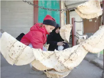  ?? COOLING FOOD: — Reuters ?? People hang bread for cooling in Aleppo, Syria.