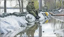  ?? CP PhOTO ?? Two soldiers sit on a dam built along the Riviere des Prairies in the Pierrefond­s borough of Montreal.