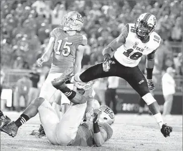  ?? Gina Ferazzi Los Angeles Times ?? UTAH’S ERIC ROWE leaps over UCLA’s Alex Redmond as Bruins kicker Ka’imi Fairbairn ( 15) misses a 50- yard field goal on the final play of the game, which Utah won 30- 28 at the Rose Bowl on Saturday.