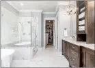  ??  ?? Dominating the master bath are white marble-tile flooring and a spacious double-sink vanity divided by a linen cabinet.