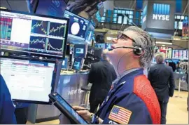  ?? Spencer Platt ?? TRADERS WORK on the f loor of the New York Stock Exchange this week. The benchmark Standard & Poor’s 500 index tumbled 5.1% in January.