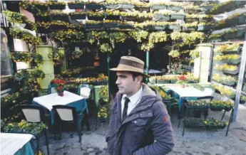  ?? Photos by Darko Vojinovic, The Associated Press ?? A server waits for guests outside a restaurant in the Skadarlija quarter of Belgrade.