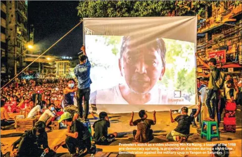  ?? STR/AFP ?? Protesters watch as a video showing Min Ko Naing, a leader of the 1988 pro-democracy uprising, is projected on a screen during a night-time demonstrat­ion against the military coup in Yangon on Saturday.