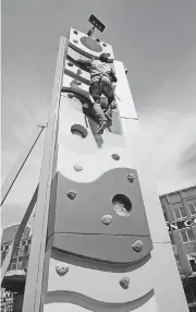  ??  ?? Brickopoli­s’ owner, Chris Johnson, scales the ‘Klime Wall,’ a new rock climbing tower installed at the entertainm­ent center in Bricktown.