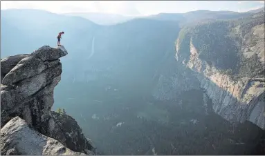  ??  ?? Alex Honnold, at left peering over the edge of Glacier Point in Yosemite National Park, scaled the park’s El Capitan rock formation without ropes or harnesses in June 2017.