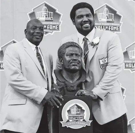  ?? KENNETH K. LAM/BALTIMORE SUN ?? Jonathan Ogden, right, and his presenter Ozzie Newsome, left, pose with Ogden's Hall of Fame bust after his induction in 2018.