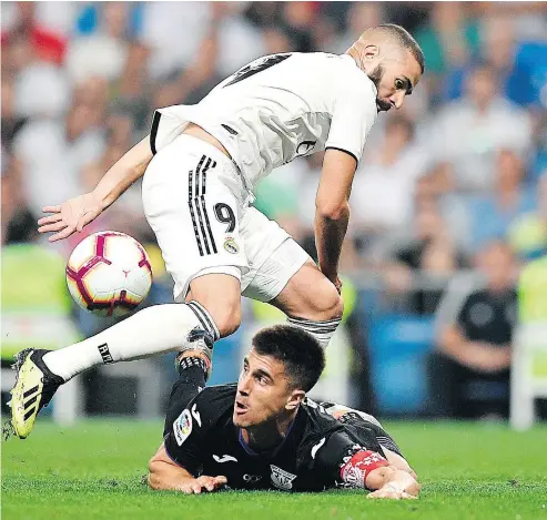  ?? GABRIEL BOUYS/AFP/GETTY IMAGES ?? Real Madrid’s Karim Benzema, standing, challenges Leganes defender Unai Bustinza during the Spanish league match between Real Madrid CF and Club Deportivo Leganes SAD in Madrid on Saturday.