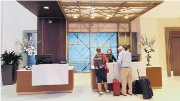  ?? TED S. WARREN/ASSOCIATED PRESS ?? Guests stand at the front desk at the Embassy Suites by Hilton hotel in Seattle’s Pioneer Square neighborho­od. Automatic elite status in hotel loyalty programs is an increasing­ly common feature on credit cards associated with these programs.