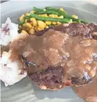  ??  ?? Monday is meatloaf day for Kettle Range's heat-and-eat meals. They change weekly; this is patty melt meatloaf, with bits of melting Swiss inside, sold with mashed red potatoes and corn with green beans.