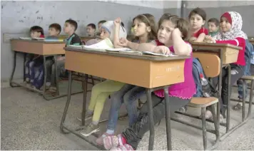  ?? — AFP ?? Syrian children attend a class at a primary school in Aleppo’s rebel-held eastern district of Shaar on Saturday. Displaced families returned home and schools reopened in rebel-held districts of Aleppo after a truce was extended for 72 hours in the...