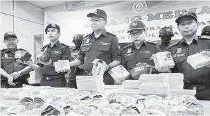  ?? — Gambar Bernama ?? DIRAMPAS: Zulkifli (tiga kiri) menunjukka­n bungkusan dadah bernilai RM18,330,000 yang dirampas di pintu masuk Kompleks Kastam, Imigresen dan Kuarantin (KIK) Bukit Kayu Hitam pada 23 Mei lalu.