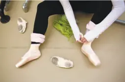  ??  ?? Raffaele Morra of Les Ballets Trockadero de Monte Carlo, top, teaches a master class in one of the company’s signature works, “The Dying Swan.” Sharon Mulligan of Oakland, above, laces up her ballet shoes.